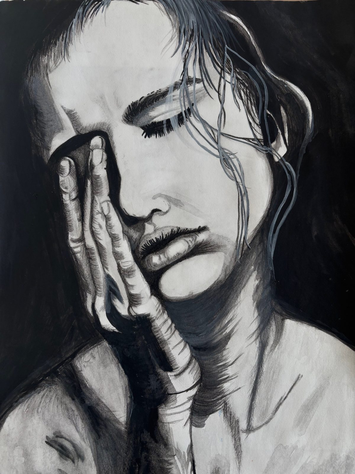 Black and white portrait of a woman with eyes closed, pressing her hand against her cheek